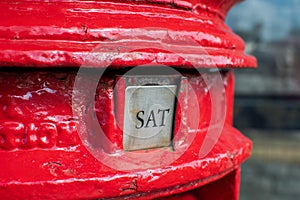 Saturday word shown as SAT on a British red letter box.