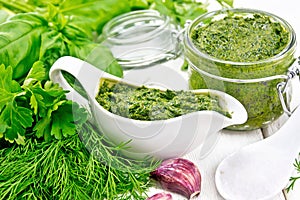 Sauce of spicy greens in gravy boat and jar on board