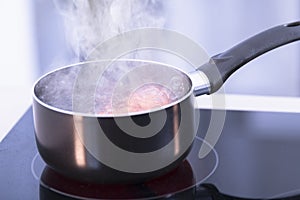 Saucepan with boiling water on a glass ceramic cooktop