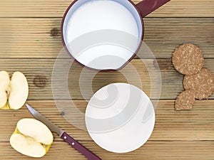 Saucepan with hot milk and bowl to breakfast