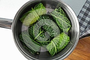 Saucepan with stuffed cabbage leaves on table