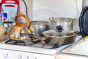 Saucepans, a frying pan and a kettle on gas stove. Dishes in the kitchen