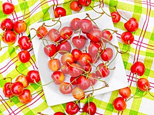 Saucer with cherries on the kitchen towel. Top view