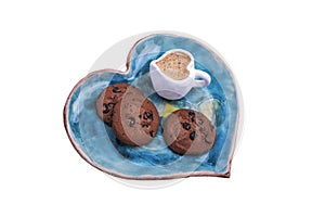 Saucer and cup with coffee in the shape of heart and cookies.