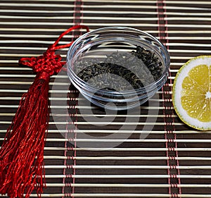 Saucer with leaves of tea and the cut lemon on a rug