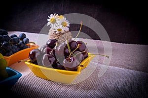 Saucers with cherry grapes, a bouquet of flowers on the table