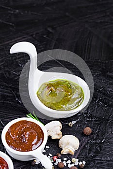 Sauces in cups on a black background. different sauces of red and orange color on a black stone board with spices