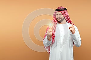 A Saudi Arab man holds a light bulb in his hand as a symbol of the idea in national dress. Dishdasha, kandora, thobe, islam. Copy