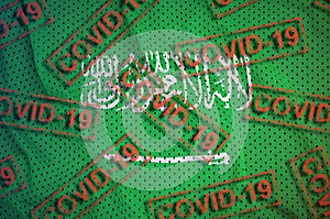 Saudi Arabia flag and many red Covid-19 stamps. Coronavirus or 2019-nCov virus concept