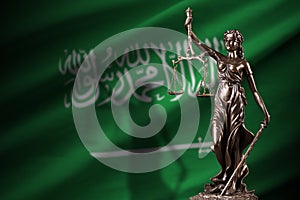 Saudi Arabia flag with statue of lady justice and judicial scales in dark room. Concept of judgement and punishment