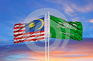 Saudi Arabia and Malaysia two flags on flagpoles and blue cloudy sky