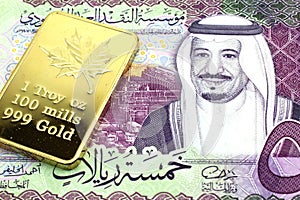 A Saudi Arabian riyal note with a gold bar in macro photo
