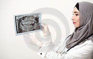 Saudi female dantist looking at teeth radiograph