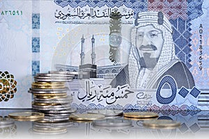 Saudi Riyal coins in front of five hundred riyal.