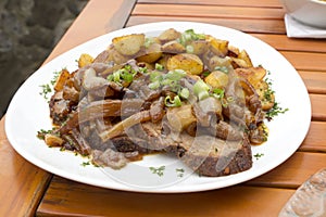 Sauerbraten with fried onions and fried potatoes on plate photo