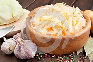 Sauerkraut with carrot in wooden bowl, garlic, spices