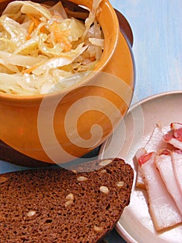 Russian traditional cuisine : Sauerkraut in a ceramic barrel pot with break and lard close up