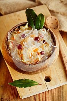 Sauerkraut - Sour cabbage - on wooden bowl with bay leaves