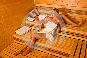 Sauna two women relaxing lying wrapped towel