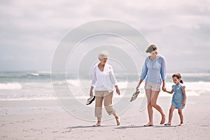 Sauntering across the sand. Portrait of a woman with her daughter and mother at the beach. photo