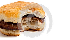 Sausage biscuit with a bite out on white
