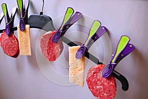 Sausage and cheese on a hanger hung on pegs, sausage and sliced cheese