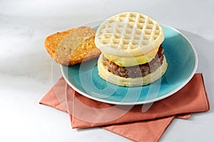 Sausage egg cheese waffles sandwich on a plate with napkin