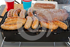 Sausage & Hamburgers Cooking On Portable Grill