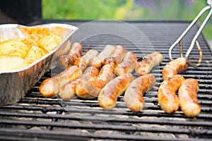 Sausage, hot dogs and potatoes on grill