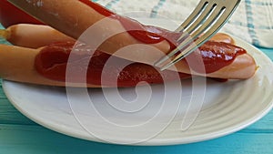 Sausage with ketchup plate fork slow motion