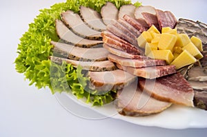 Sausage, meat, roll and cheese, decorated with lettuce leaves on a white plate