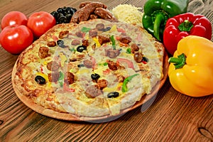 Sausage and minced meat pizza pie with bell pepper, tomato and black olive served in wooden board isolated on table side view of