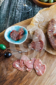 Sausage on parchment, dried tomatoes and olives