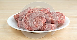 Sausage patties on a white plate atop a table