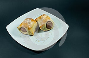 Sausage roll in the dough on a white plate