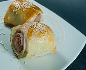 Sausage roll in the dough on a white plate