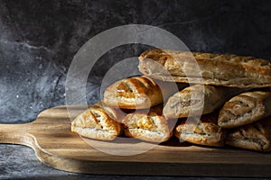 Sausage rolls, freshly baked and cooling on a wooden chopping board.