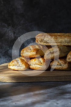 Sausage rolls, freshly baked and cooling on a wooden chopping board.