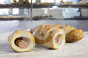 Sausage Rolls With Sesame Cut in Half on Floury Wooden Table