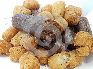 Sausage with tater tots and salt and pepper in white container