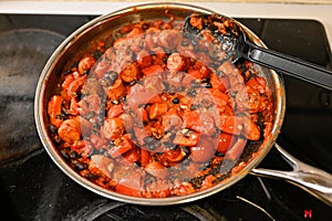 sausage and vegetables cooking in fryingpan on stove