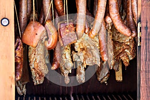 Sausages and bacon inside wooden smokers