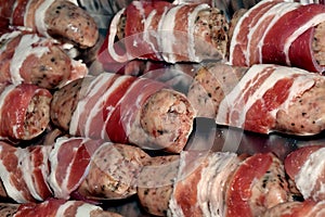 Sausages with bacon prepared to cook on baking tray.