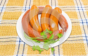 Sausages with branch of coriander on a white dish