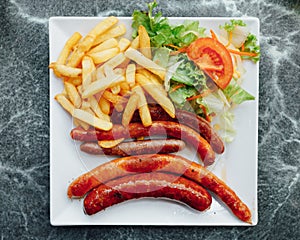 sausages, french potato fries and salad on plate