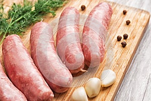 Sausages for frying, garlic and dill on a bamboo cutting board