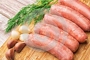 Sausages for frying, garlic, dill with a wooden cutting board
