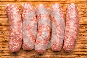 Sausages for frying on a wooden cutting board, top view