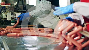 Sausages are getting removed from the factory transporter at a meat factory.