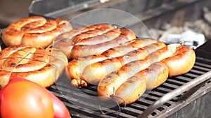 Sausages on a grill with tomatoes and sweet peppers